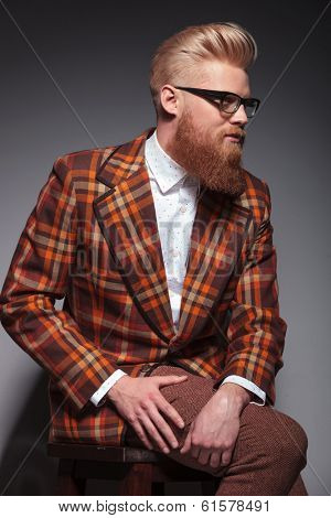 side view of a dramatic beauty fashion male model with long beard and cool hairstyle looking away from the camera