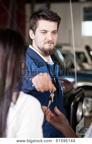 Handsome car mecanic giving back the keys to the client