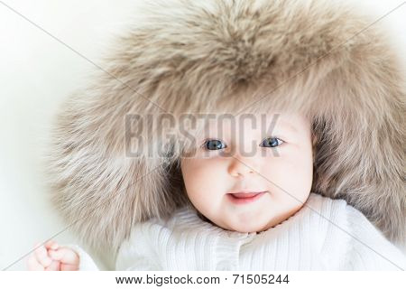 Happy Little Baby In A Huge Fur Hat On A White Blackground