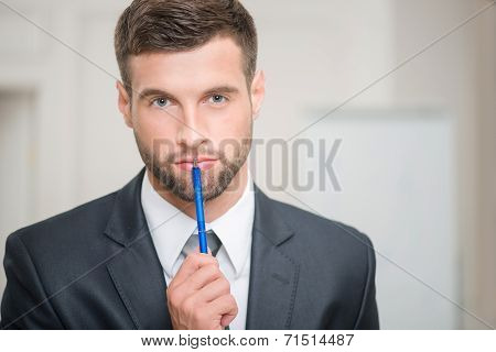 Portrait of handsome businessman in office interior touching his