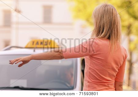 woman raising her arm to call a taxi