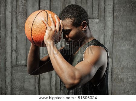 Afro-american basketball player pressing ball to his forehead
