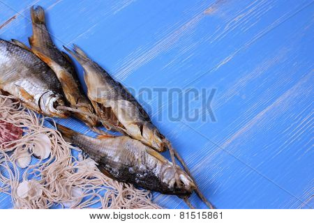 Dried Rudd Fish And Fishing Net On Blue Background