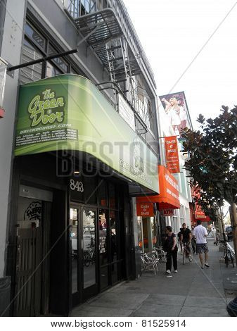 People Move Along The Sidewalk In Front Fo The Green Door, Medical Marijuana Pot Shop Store In Soma
