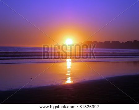 Epic Sunset Reflects On Ocean And Beach On An Empty Clear Sky Day