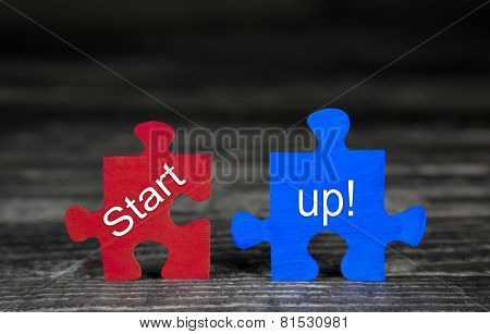 Business concept for start-up: red and blue puzzle on wooden background with text. 
