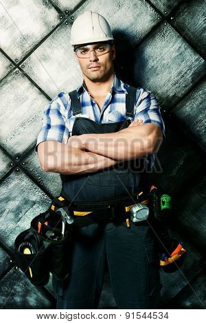 Handsome costruction worker wearing uniform and tools over grunge industrial background. Job, occupation. 