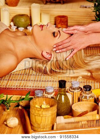 Woman with eyes clased getting facial massage in tropical beauty spa.