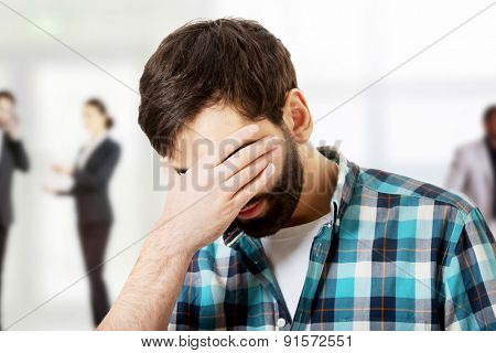Young upset man covering his face.