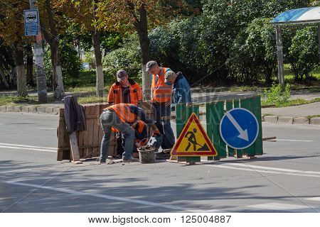 Kiev Ukraine - September 10 2015: Utility workers in orange vests repair asphalt on the road