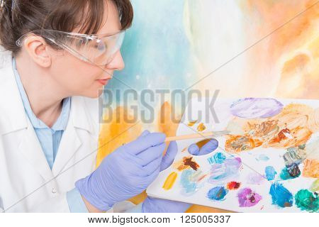 Artwork conservator at work with old painting wearing protective suit