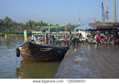 HOI AN, VIETNAM - JANUARY 04, 2016: People and vehicles are loaded on a city ferry for the crossing to the other side by the Thu Bon river