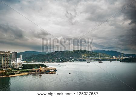 Picturesque landscape with a view on Tsing Ma Bridge, Hong Kong, China. A view with urban and industrial merging with natural mountaings on islands and gorgeous clouds.
