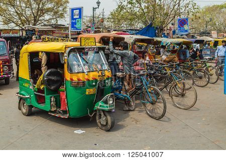 DELHI INDIA - 19TH MARCH 2016: Tuk Tuk Rickshaws parked on a street in central Delhi during the day. People can be seen.