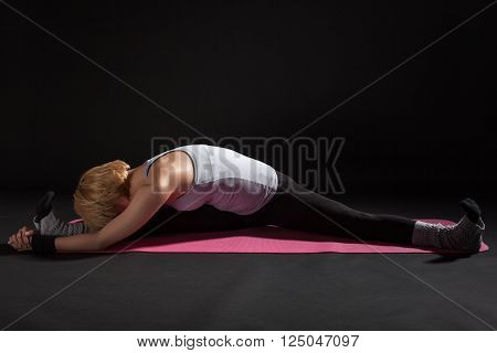 Young woman practicing yoga, variation of Upavistha Konasana / Seated Angle Pose