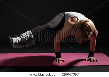 Young woman practicing yoga, Astavakrasana / Eight Angle Pose