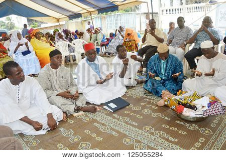 Abidjan, Ivory Coast - February 26, 2015: Religious leaders are doing the last prayer to bless the newlyweds. Sitting on mats placed on the floor, religious leaders, open and outstretched hands made their last prayer for the succeful mariage.