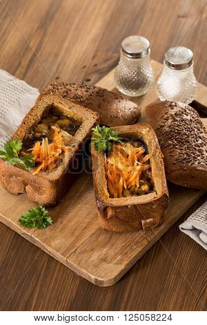Fresh pea soup in a Bread Bowl, on a wooden board with salt and papper