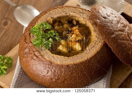 Fresh pea soup in a Bread Bowl, on a wooden board with salt and papper