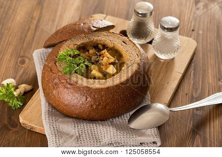 Fresh pea soup in a Bread Bowl, on a wooden board with salt and papper