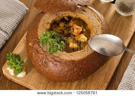 Fresh pea soup in a Bread Bowl, on a wooden board with salt and papper