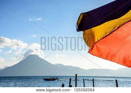 Colorful umbrella & San Pedro volcano in evening light at Lake Atitlan in Guatemalan highlands.