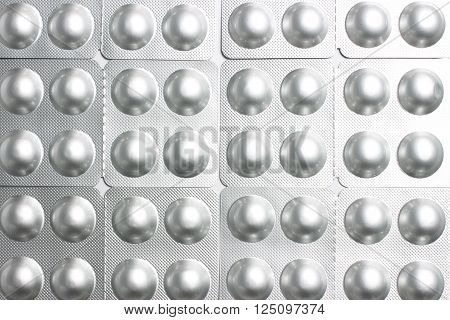 Background of round pills in silvery blisters