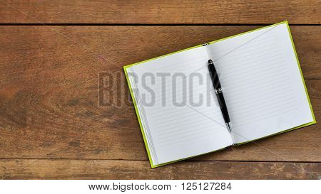 Top view workspace with blank notebook and pen on wooden table background .