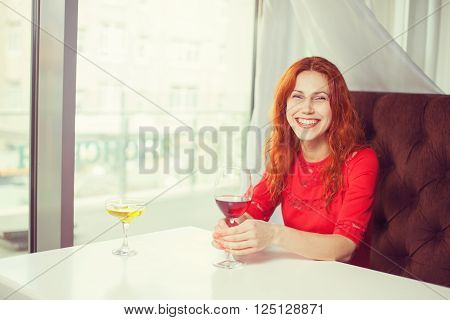 Portrait of a smiling young woman holding a glass of red wine.
