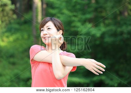 portrait of Japanese woman outside doing stretches exercise