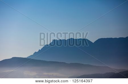 foggy hilly ground in front of a mountain chain