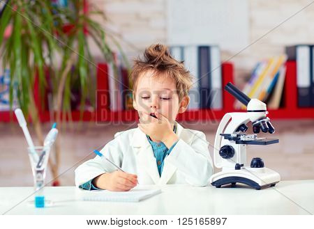 surprised kid boy writing notes after experiment in school lab