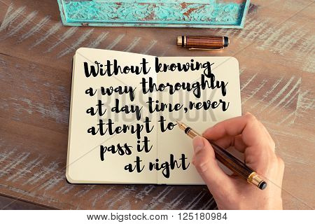 Retro effect and toned image of a woman hand writing on a notebook. Handwritten quote Without knowing a way thoroughly at day time, never attempt to pass it at night as inspirational concept image