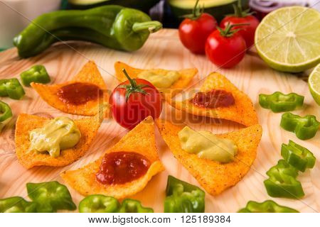 Close up of nachos chips and vegetables over a chopping board