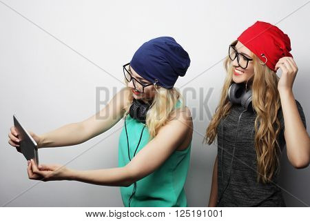 two hipster girls friends use digital tablet, studio shot over gray vackground