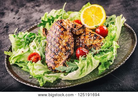 Grilled chicken breast in different variations with lettuce salad cherry tomatoes .mushrooms herbs cut lemon on a wooden board or grill pan. Traditional cuisine. Grill kitchen.