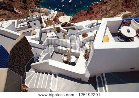 grey and white staircases leading down to beautiful Amoudi bay in volcanic village Oia, Santorini, Greece.