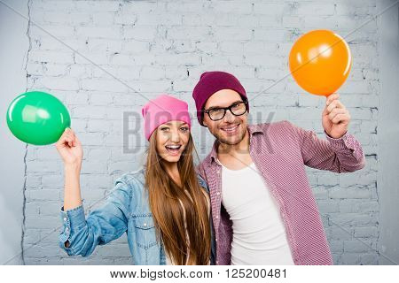 Happy Hipster Young Man And Woman Celebrating With Balloons