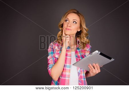 Portrait of attractive minded woman with tablet dreaming about smth