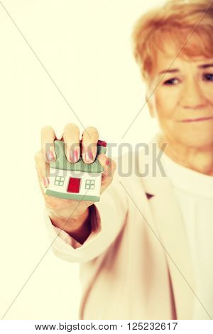 Elderly angry business woman crushed house model