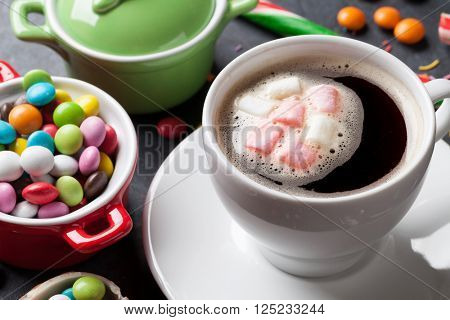 Colorful candies and coffee cup on stone background