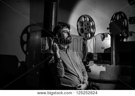 beautiful hipster man standing near a film projector in the room projectionist