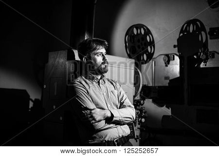 man standing near a film projector in the room projectionist