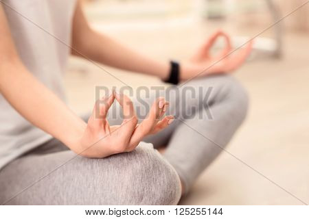 Find the harmony. Close up of handoff pleasant girl holding it on her knee while sitting on the floor and practicing yoga
