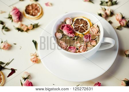 Herbal Tea In White Cup And Saucer With Roses And Dried Flowers Dried Round Slices Of Lemon Laid On