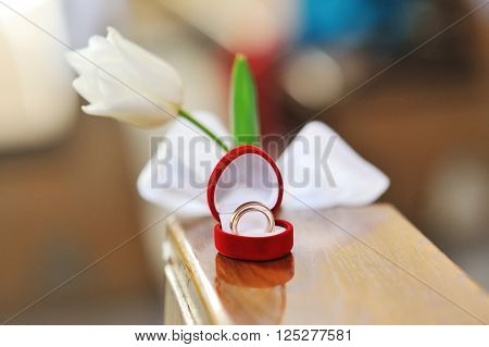 wedding rings in a heart shaped box and flower.