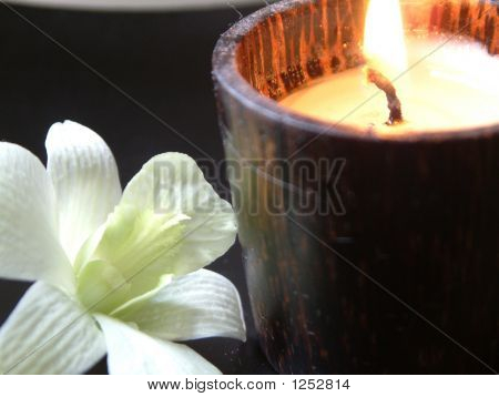 Candle Burning With White Orchid