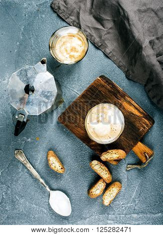 Glasses of coffee with ice cream on rustic wooden board, steel Italian Moka pot over grey concrete textured background, top view