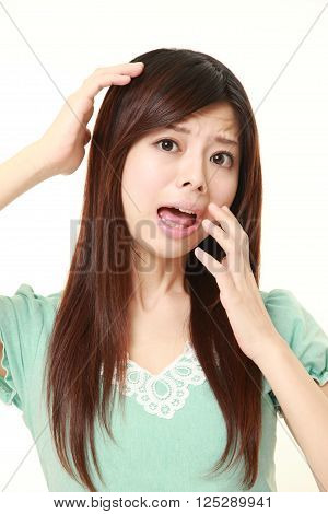 portrait of young Japanese woman shocked on white background