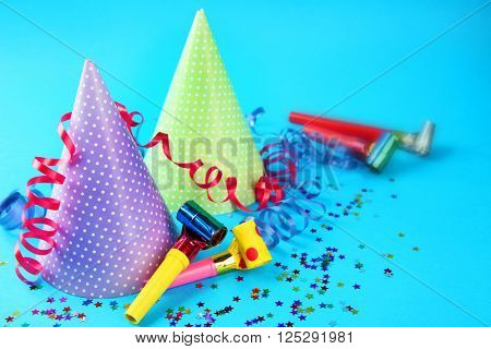 Two Birthday hats with serpentine streamer and noise makers on blue background